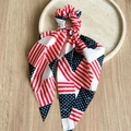 Detail of USA flag pattern scrunchie with ribbons on a beige tray over wooden desk - Star Stripe Red