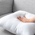 Soft white square pillow insert being pressed on a grey sofa for plushness - Square Pillow Core