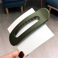 Elegant dark green oval matte hair claw clip for women shown in a hand-held view - Green