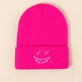 Detailed close-up of rose red ribbed knit beanie featuring white embroidered smiley face - One Size / Rose Red