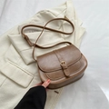 Chic brown leather saddle bag with metal buckle and adjustable strap on a beige blazer - Khaki