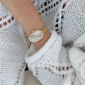 Close-up of a gold oval quartz watch on a wrist with a soft white knitted background - Single-Gold Case White Dial