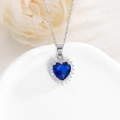 Vista macro di un ciondolo a cuore in zircone blu con contorno di diamanti bianchi scintillanti - Blu Reale
