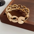 Detalle de eslabones metálicos dorados en S en una pulsera elástica de moda - Dorado