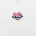 Detailed macro view of an enamel pink heart planet brooch with blue rings on a card - 77*Heart Shaped Pink Planet Pin
