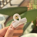 Detailed view of a mini cream bow hair claw clip with golden metal spring held in hand - Cement Gray-Bow Style