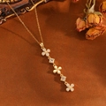 Gros plan d'un collier trèfle doré avec des diamants et un décor floral rétro élégant - Collier Fleur à Gland Doré