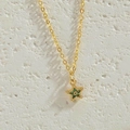 Macro shot of a gold-plated necklace with a vibrant green star-shaped zircon pendant - Green Zirconia