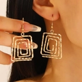 Dettaglio di orecchini a spirale rettangolare dorata indossati con ganci su una modella - Stile Rettangolo a Onde (1862)