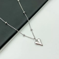 Detailopname van een gepolijste hartvormige hanger aan een kralenketting in zilver - Hart Kralen O-ketting / Staalkleur