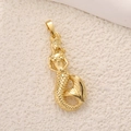 Vue détaillée d'un pendentif sirène plaqué or posé sur un fond beige texturé - Sirène Dorée