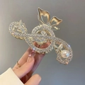 Detail of a gold music note hair claw clip with white rhinestones and a large pearl - Music Note