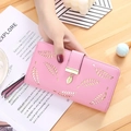 Pink long wallet for women with golden leaf pattern and pendant on a bright wooden desk - Pink Purple