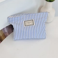 Dettaglio del beauty case a righe blu in tela con etichetta Pleasant Time e zip - Righe blu e bianche