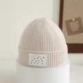 Detail of cream ribbed knit kids hat with fashion alphabet label on display stand - 1-4 Years / White