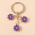 Llavero dorado con tres pequeños colgantes de margaritas de esmalte color púrpura - Morado