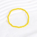 Close-up of yellow beaded bohemian bracelet on a white textured background - Yellow