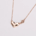 Primer plano de collar en oro rosa con colgante de corazón geométrico y letra e minúscula - Oro rosa