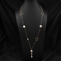 Long collier doré élégant avec perles baroques et anneaux géométriques sur buste noir - Sautoir asymétrique couleur contrastée