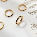 Dettaglio di anelli d'oro con smalto a cuore nero e pietre nere su carta artistica - US 6 / Zirconia Nera Doppia