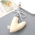 Detail of PU leather heart pendant with pearl bow and silver heart charm on grey desk - White
