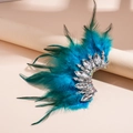 Dettaglio dell'orecchino con piume blu e cristalli su supporto espositivo beige - Polsino per Orecchio con Piume Blu e Strass