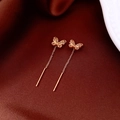 Detailed close-up of 18K gold plated butterfly earrings on elegant red silk fabric - Gold