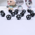 Macro shot of black round wooden beads with white paw print patterns for DIY crafts - Black Base White 4-Paw