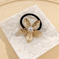 Elegant gold flower hair tie with pearl center and textured petals on a white stone base - Pearl Flower Hair Tie