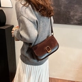 Deep brown suede and leather crossbody bag with gold buckle on casual street style model - Brown