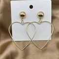 Macro detail of gold-plated heart-shaped hoop earrings on a brown satin fabric background - Large Gold Heart