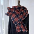 Classic red, blue and white houndstooth scarf with tassels on a black knit sweater - Red