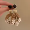 Detail van Boheemse geweven oorbellen met houten knopjes en stoffen bloemdetails - Parel Hout Rotan Stijl (Klein) / Bruin / Zilveren naald