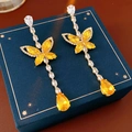 Macro view of butterfly earrings with yellow gems and crystals on a dark blue gift box - Yellow