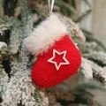 Plush red Christmas sock ornament with white star detail hanging on a snowy pine branch - Pentagram