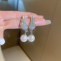 Dettaglio di orecchini ad ala in argento con zirconi scintillanti e perle bianche - Paio di Orecchini (Perno in Argento-Colore Argento)