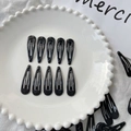 Set of classic 5cm black teardrop metal snap hair clips with glossy finish on a plate - Black