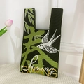 Detail of green knitted knot bag with white swallow motif and Spring text design - Spring Green