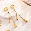 Orecchini a goccia dorati di lusso con lunghe nappe su superficie in pietra - Solo orecchini / Oro