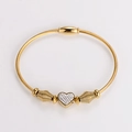 Detalle del dije de corazón dorado con diamantes sobre pulsera de cable trenzado - Dorado