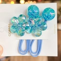 Primer plano de gomas para pelo de camelia azul con cuentas de resina brillantes y detalle - Azul Cielo