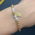 Detailed shot of beaded bracelet with Virgin Mary pendant and pearls on the wrist - Metal Virgin Mary