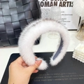 Close-up of fluffy white plush headband held by hand with high-quality faux mink fur texture - Cross Mink