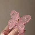 Close-up of a pink acrylic butterfly hair claw clip held against a soft background - Jelly Pink