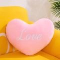 Rosa herzförmiges Plüschkissen mit Love-Stickerei auf einem gelben Sofa - 15cm / Rosa