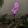 Pink flamingo solar neon garden light on a stake illuminating a backyard at night - Plastic Neon Bird