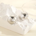 Close-up of polished silver spherical stud earrings on a creative white display stand - Silver Large Sphere / Silver
