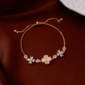 Detailed shot of adjustable gold flower bracelet with cat eye clover and zircon charms - Four-Leaf Clover Cat Eye Stone Adjustable Bracelet / Gold
