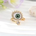 Anello malocchio dorato con zirconi verdi e cristalli scintillanti su sfondo ondulato - Aperto/Con Strass / Verde