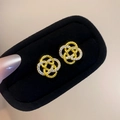 Detail of gold interlocking twist earrings with white zircon on black velvet display - Gold